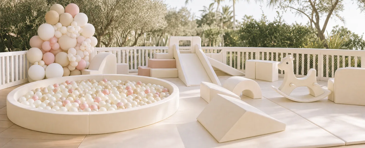A full soft play setup on a sunlit terrace: ball pit, slide, foam shapes and a rocking horse